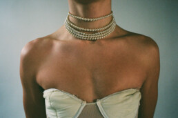 Male bust in a bustier with choker pearls.