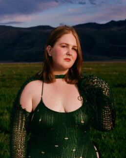 Full figured pale red head girl in a green knit slip dress standing in Idaho's Camas Prairie.